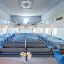 A screen shot of the interior of the Morattico Baptist Church. The image shows the interior of the church taken from the perspective of the pulpit.